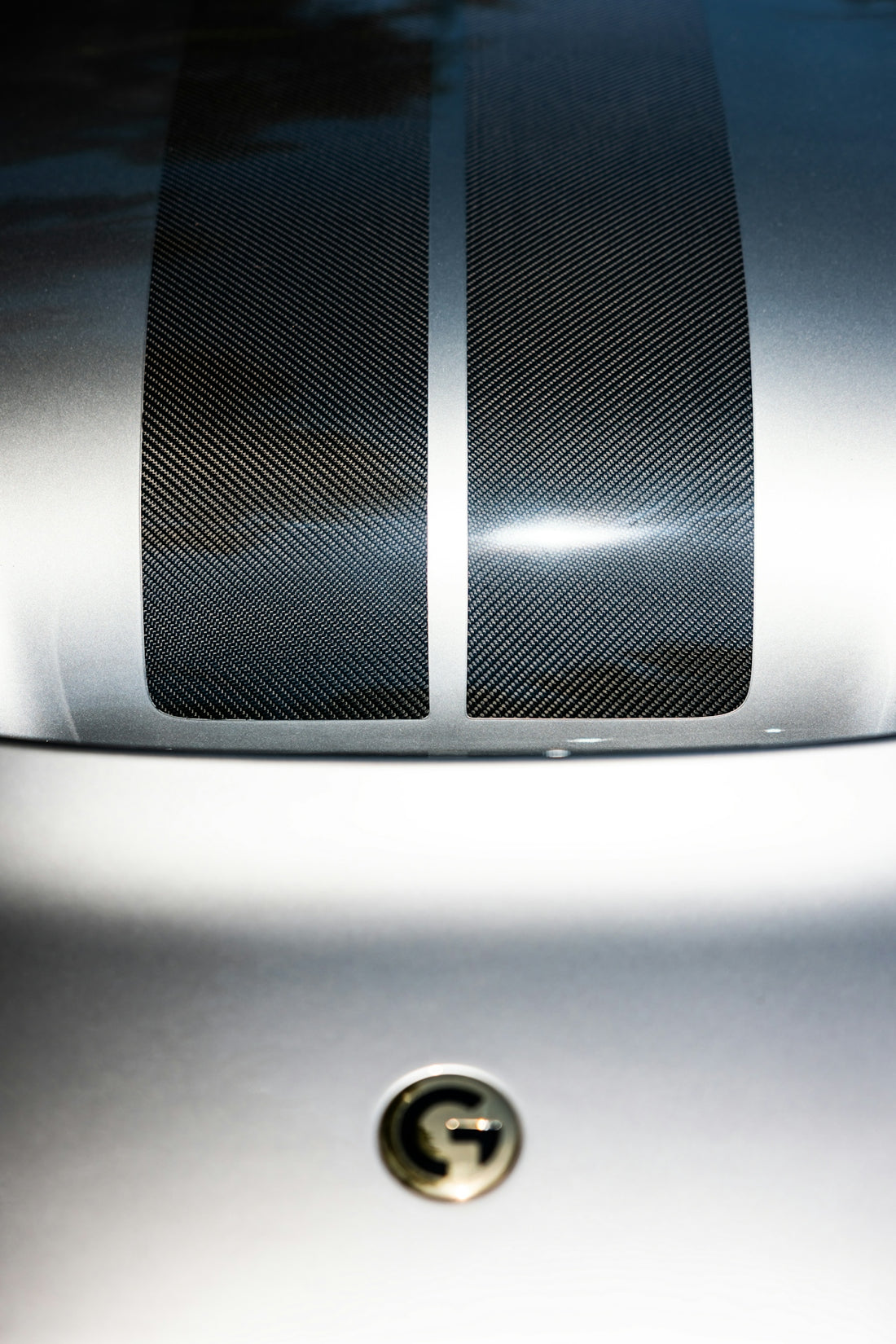Silver car hood with carbon fiber stripes.