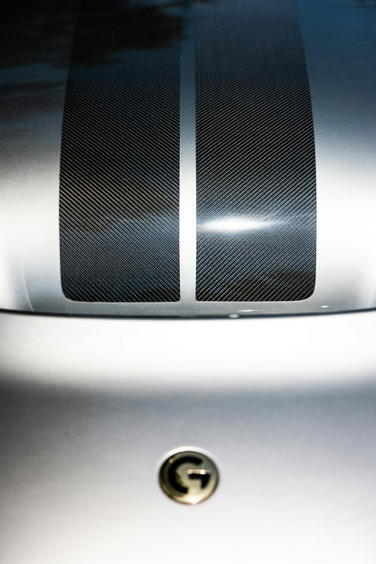 Silver car hood with carbon fiber stripes.